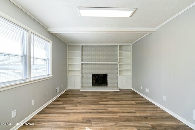 unfurnished living room featuring ornamental molding, a brick fireplace, dark wood-type flooring, and wood walls