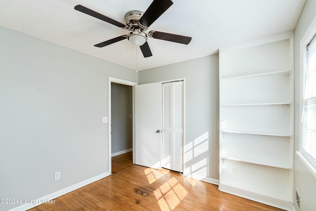 unfurnished bedroom featuring wood-type flooring, multiple windows, and ceiling fan