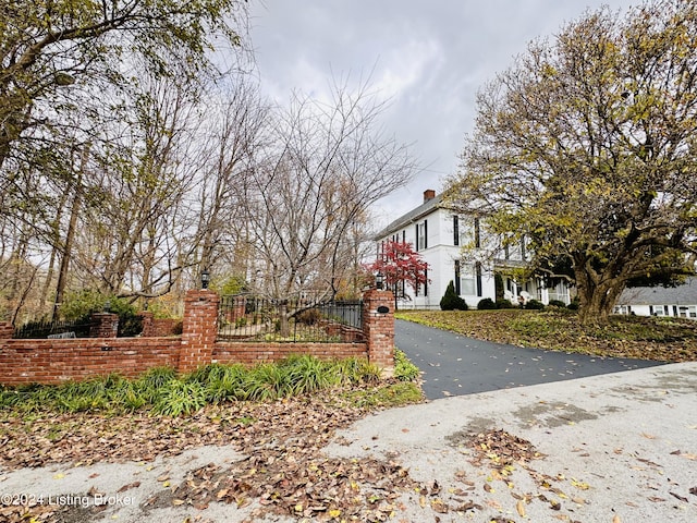 205 W Chestnut St, Leitchfield, KY 42754 - view of side of home with a fenced front yard, driveway, and a chimney
