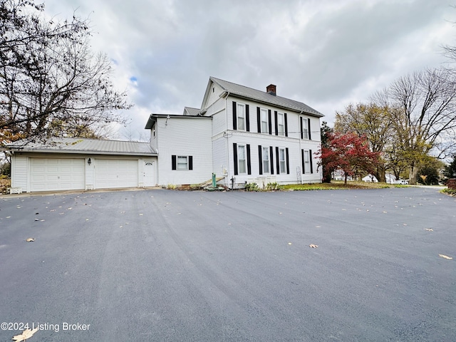 205 W Chestnut St, Leitchfield, KY 42754 - view of property exterior with a garage, a chimney, driveway, and a metal roof