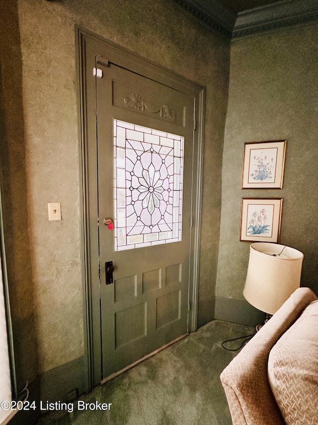 foyer entrance with crown molding and carpet