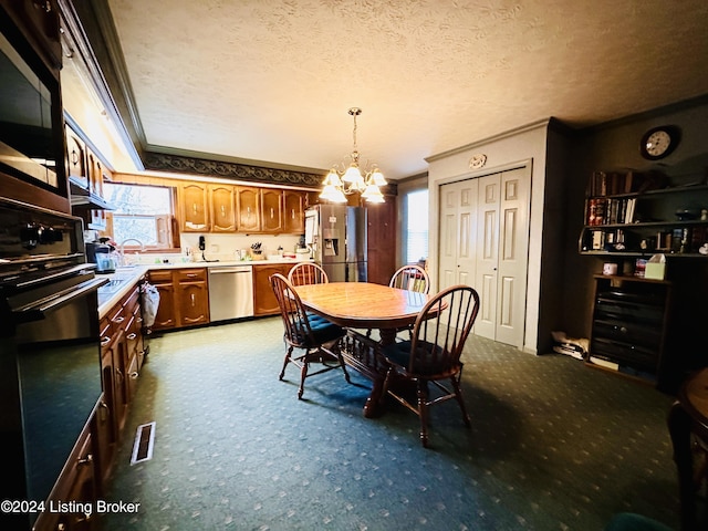 dining room with carpet flooring, ornamental molding, a textured ceiling, and a notable chandelier