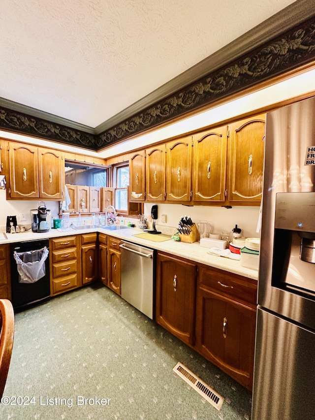 kitchen with a textured ceiling, stainless steel appliances, and ornamental molding