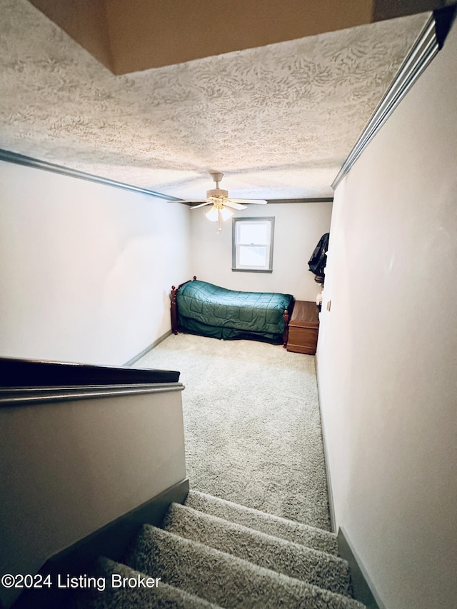 carpeted bedroom featuring ceiling fan, crown molding, and a textured ceiling