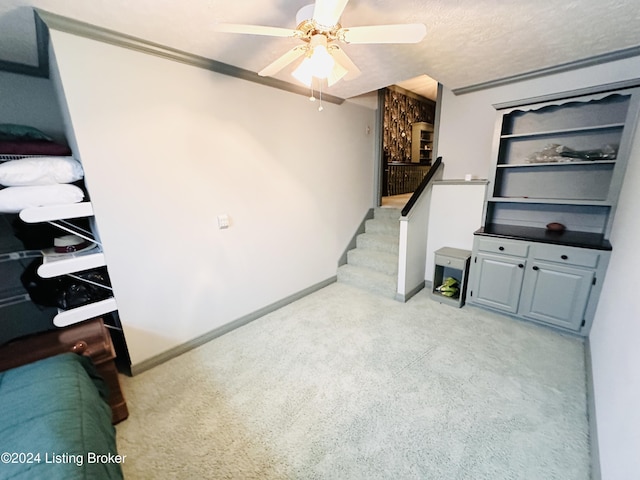 carpeted living room with a textured ceiling, ceiling fan, and crown molding