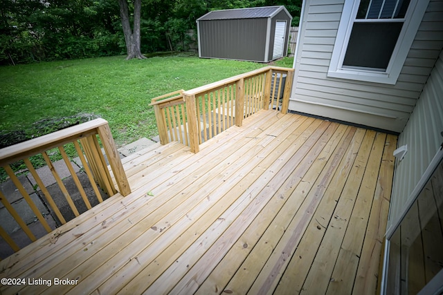 wooden deck featuring a storage unit and a lawn