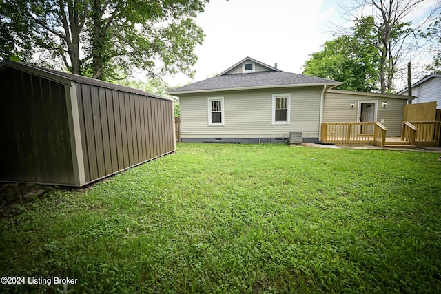 rear view of property featuring a yard, cooling unit, an outdoor structure, and a deck