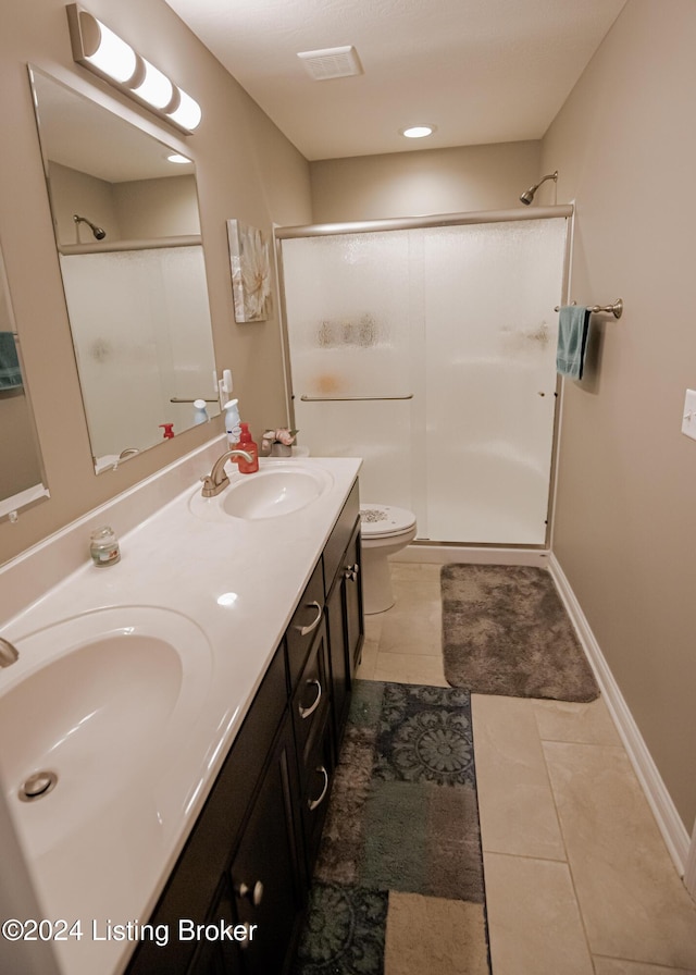 bathroom with tile patterned flooring, vanity, a shower with door, and toilet