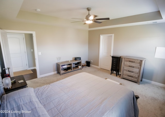 bedroom featuring ceiling fan, a raised ceiling, and light carpet