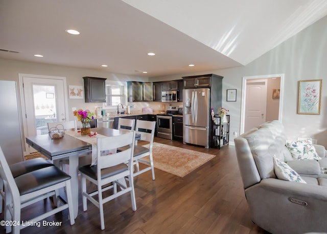 dining room with dark hardwood / wood-style flooring, vaulted ceiling, and sink