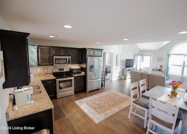 kitchen with dark hardwood / wood-style floors, light stone countertops, and appliances with stainless steel finishes