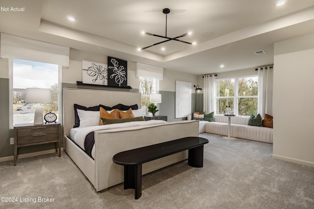 bedroom with a raised ceiling, light carpet, and a chandelier