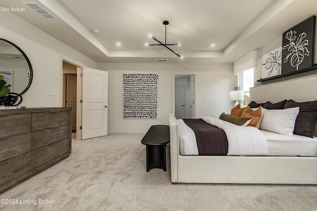 carpeted bedroom with a chandelier and a tray ceiling