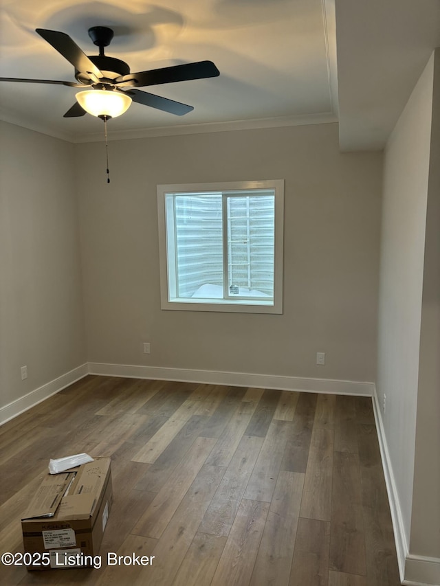 empty room with ornamental molding, a ceiling fan, baseboards, and wood finished floors