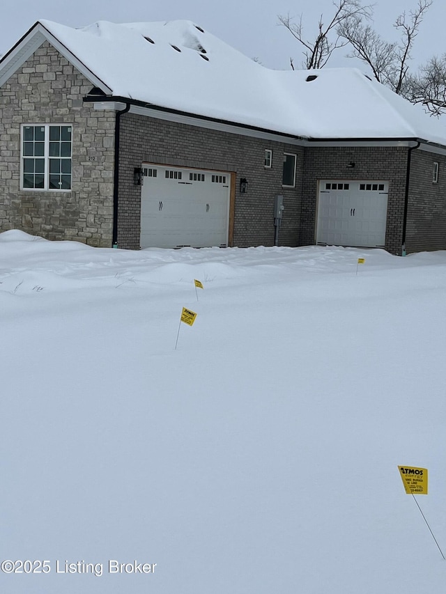 view of front of property featuring stone siding, brick siding, and an attached garage