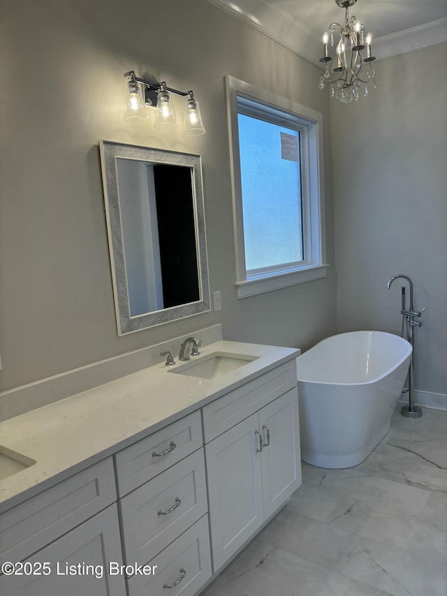 full bath featuring marble finish floor, a notable chandelier, a freestanding bath, ornamental molding, and vanity