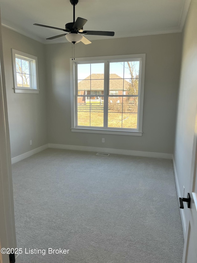 empty room with visible vents, baseboards, ceiling fan, carpet, and crown molding