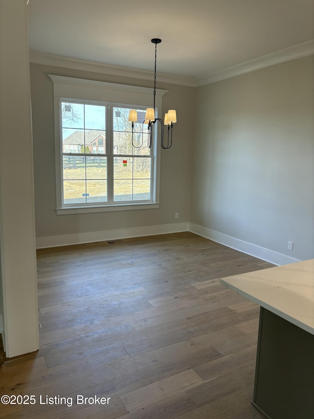 unfurnished dining area featuring baseboards, a chandelier, dark wood-type flooring, and crown molding