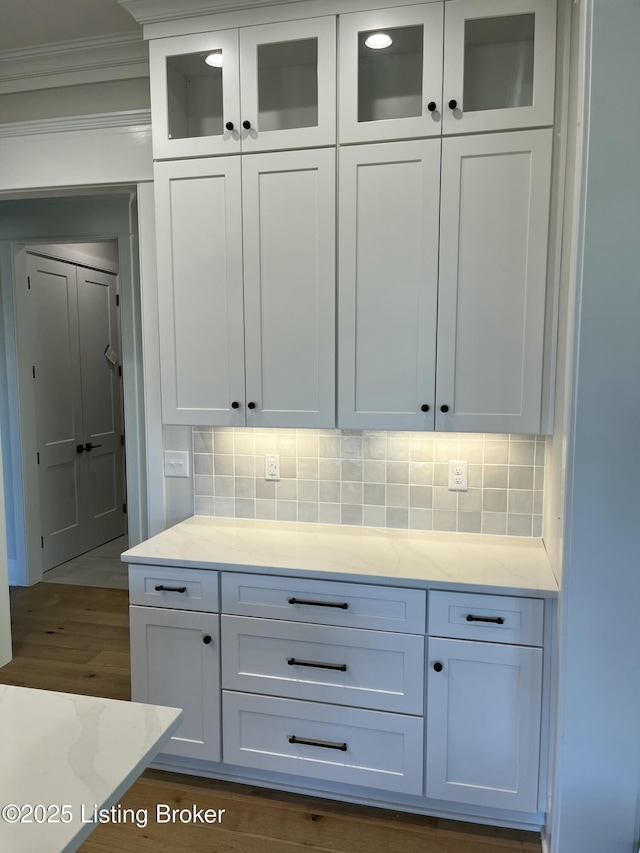 bar featuring ornamental molding, dark wood-style flooring, and decorative backsplash