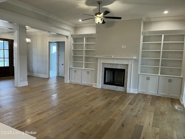 unfurnished living room featuring ornamental molding, a high end fireplace, visible vents, and hardwood / wood-style flooring