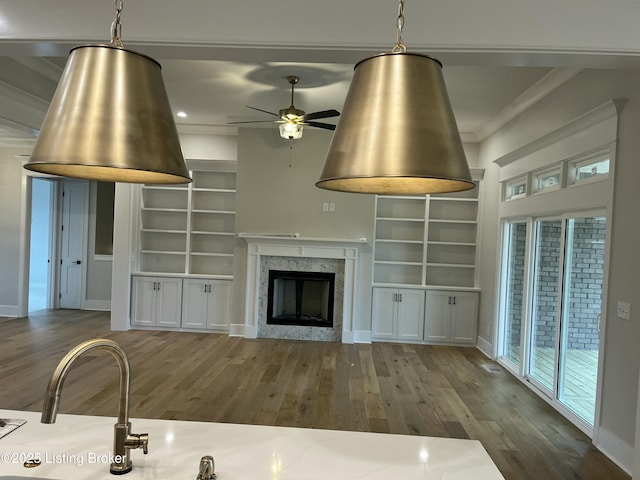 unfurnished living room featuring baseboards, a fireplace, wood finished floors, and crown molding