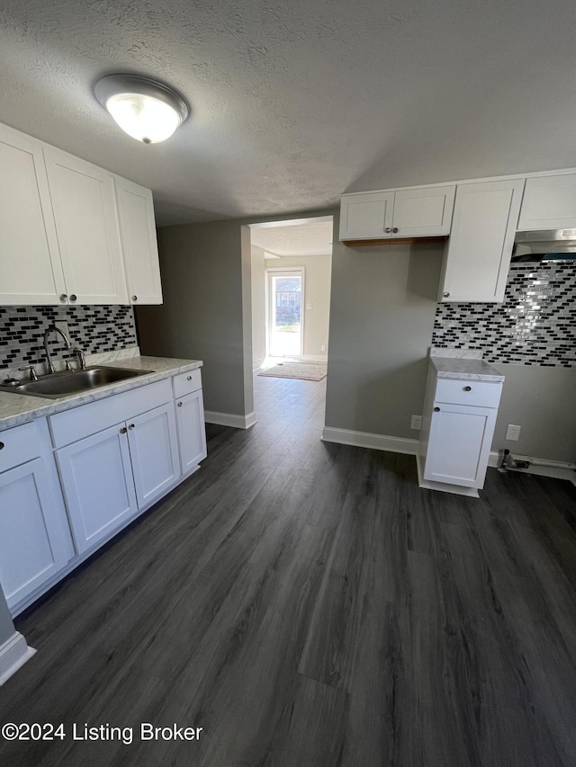 kitchen with dark hardwood / wood-style flooring, white cabinetry, and tasteful backsplash