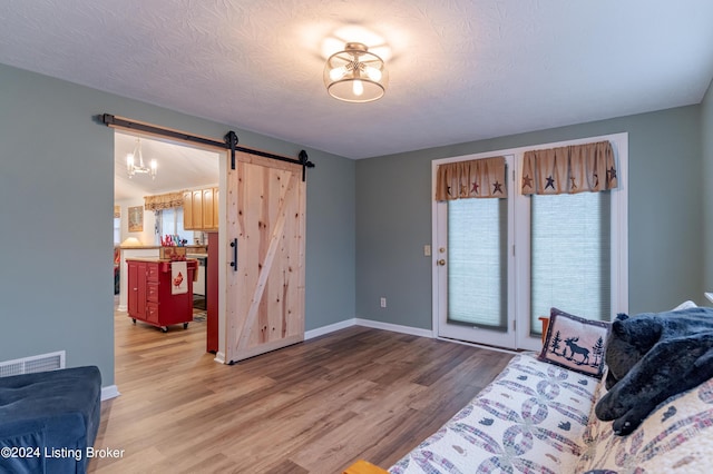 interior space featuring hardwood / wood-style floors, a barn door, a textured ceiling, and an inviting chandelier