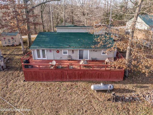 rear view of property with a deck and a storage unit