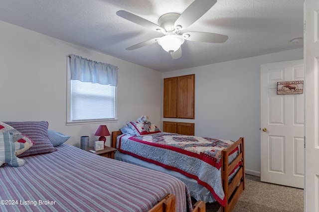 bedroom with a textured ceiling, light colored carpet, and ceiling fan