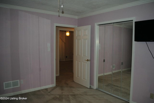 unfurnished bedroom featuring a closet, light colored carpet, a textured ceiling, and ornamental molding