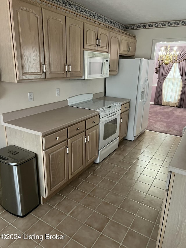 kitchen with dark tile patterned flooring, white appliances, and an inviting chandelier