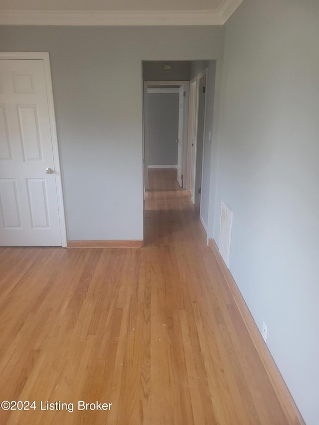 empty room with light wood-type flooring and ornamental molding