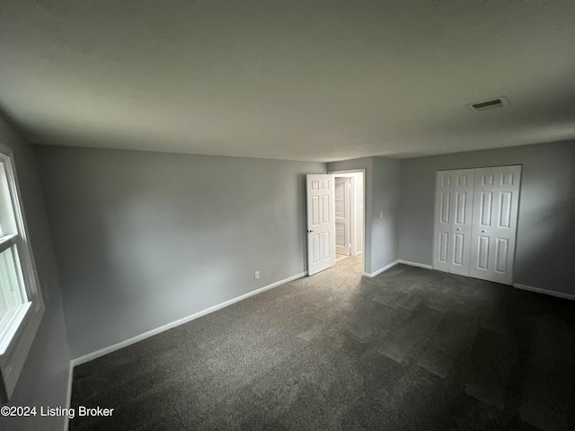 unfurnished bedroom with a closet and dark carpet