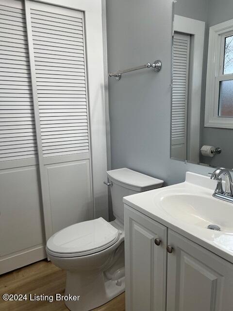 bathroom with hardwood / wood-style flooring, toilet, and vanity