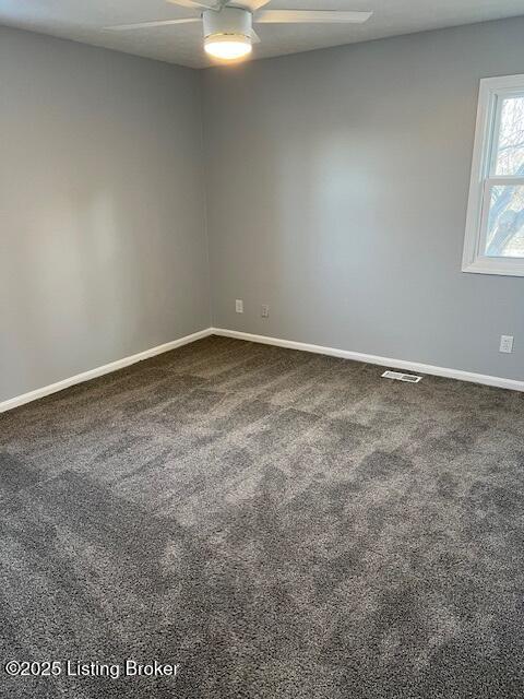 spare room featuring ceiling fan and dark colored carpet