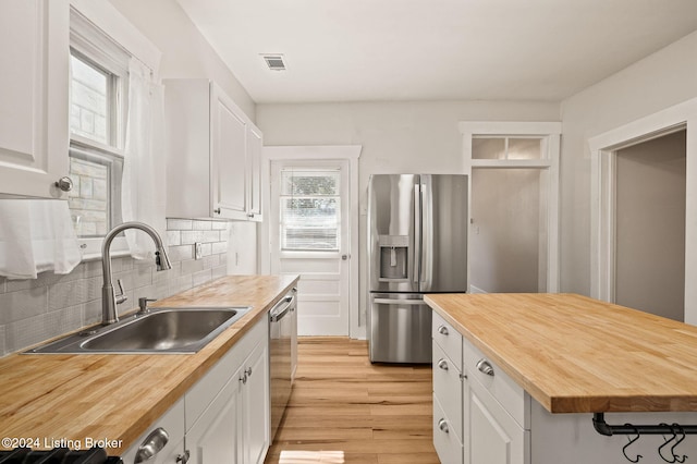 kitchen with a healthy amount of sunlight, white cabinetry, sink, and stainless steel appliances