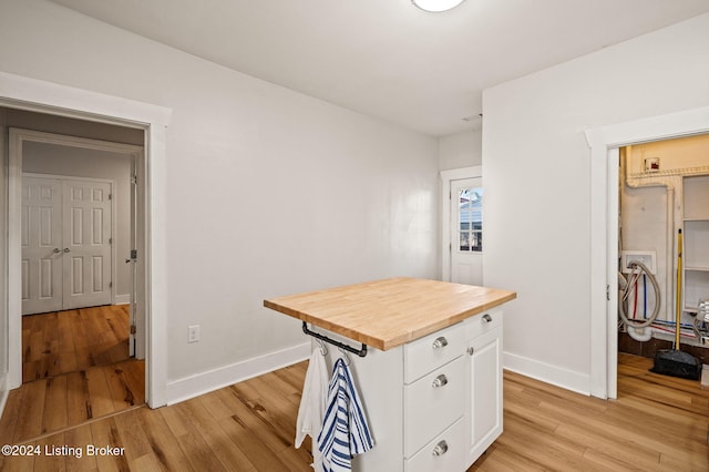 interior space featuring butcher block counters, white cabinetry, a center island, and light hardwood / wood-style floors