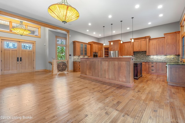 kitchen featuring hanging light fixtures, tasteful backsplash, light hardwood / wood-style flooring, a kitchen island, and appliances with stainless steel finishes