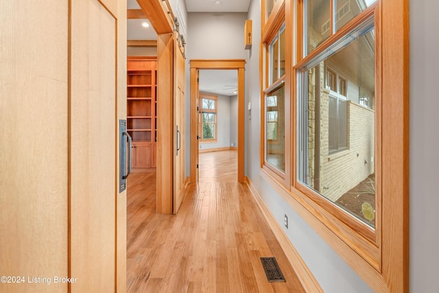 corridor featuring a barn door and light hardwood / wood-style floors