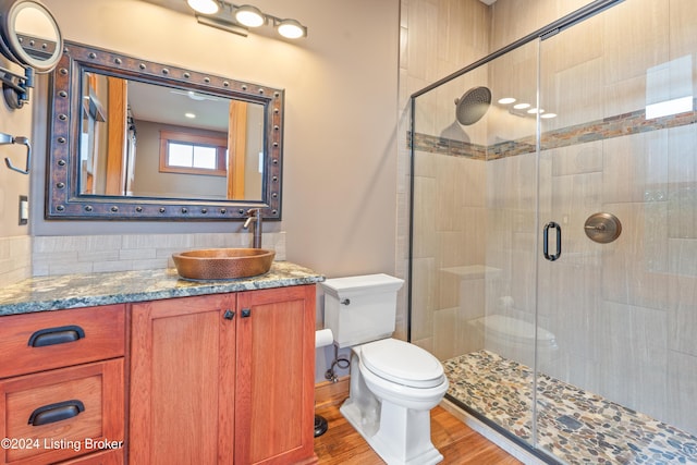 bathroom featuring wood-type flooring, vanity, toilet, and walk in shower