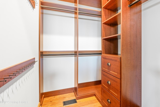 walk in closet with light hardwood / wood-style floors