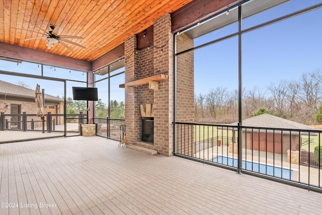 unfurnished sunroom featuring a fireplace, ceiling fan, and wood ceiling