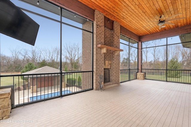 unfurnished sunroom with ceiling fan, wood ceiling, and an outdoor brick fireplace