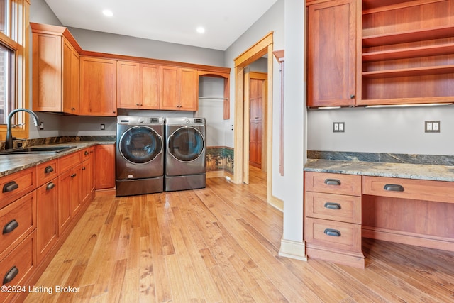 washroom featuring washing machine and dryer, cabinets, sink, and light hardwood / wood-style floors