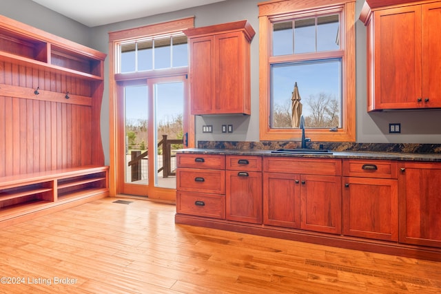 kitchen with light wood-type flooring, sink, and dark stone counters