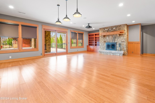 unfurnished living room featuring a stone fireplace and light hardwood / wood-style floors