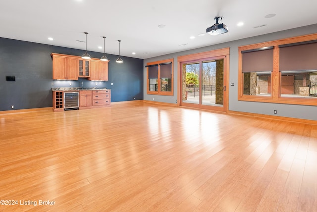 unfurnished living room with bar, light wood-type flooring, and wine cooler