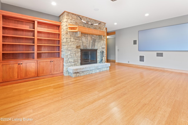 unfurnished living room featuring a stone fireplace and light wood-type flooring