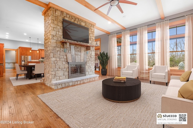 living room featuring beamed ceiling, light wood-type flooring, ceiling fan, and a fireplace