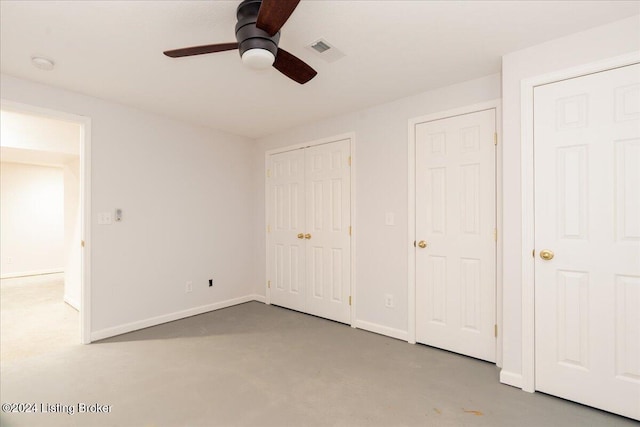 unfurnished bedroom with concrete floors, two closets, and ceiling fan